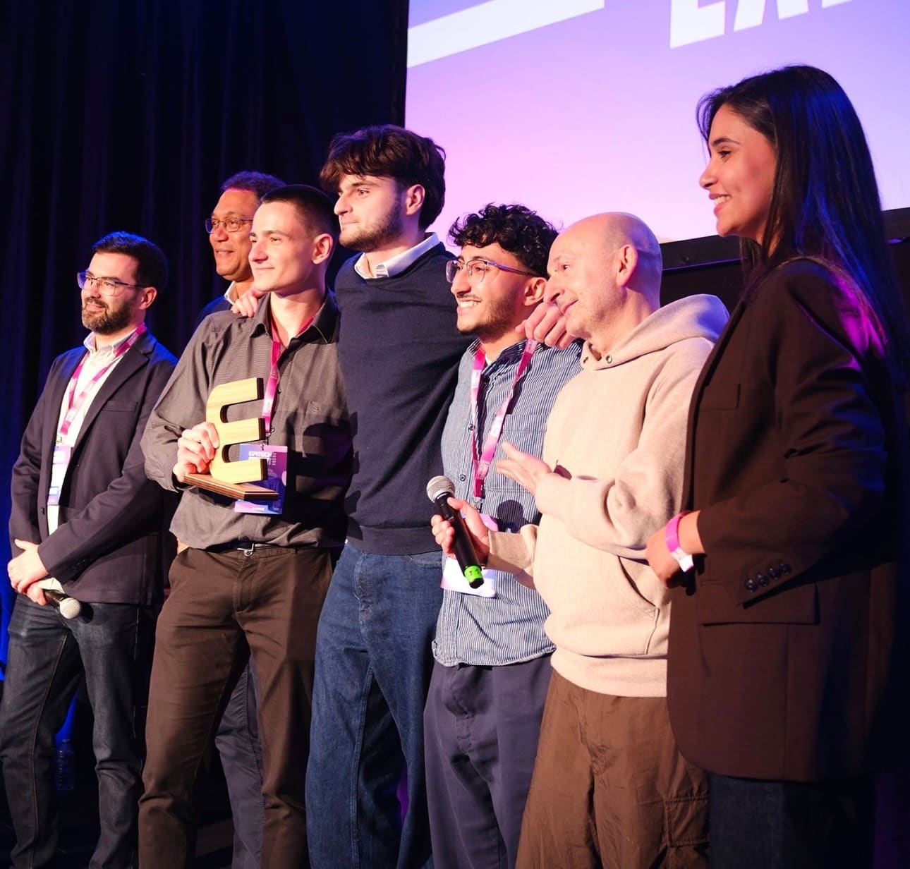 William Stoops, the first-place trophy in hand, surrounded by six people on the Epitech Summit stage
